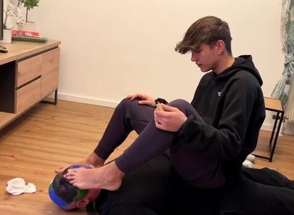 German master sitting on feet licking boy